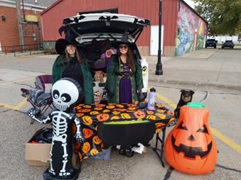 Two women in clothing standing in the trunk of a car
AI-generated content may be incorrect.